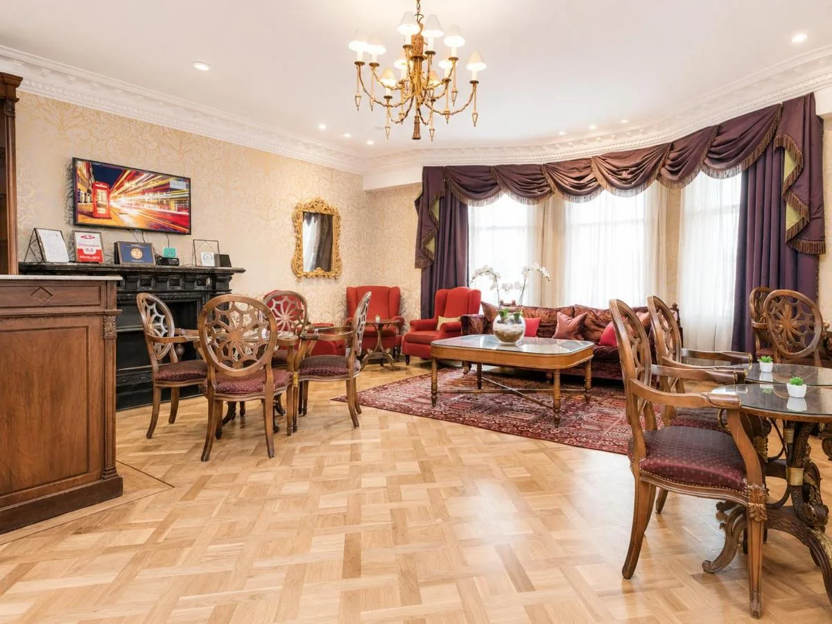 a living room with a couch and a table and chairs at Ashburn Hotel in London